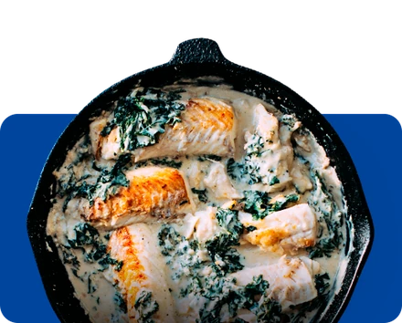 Creamy fish with greens in a skillet